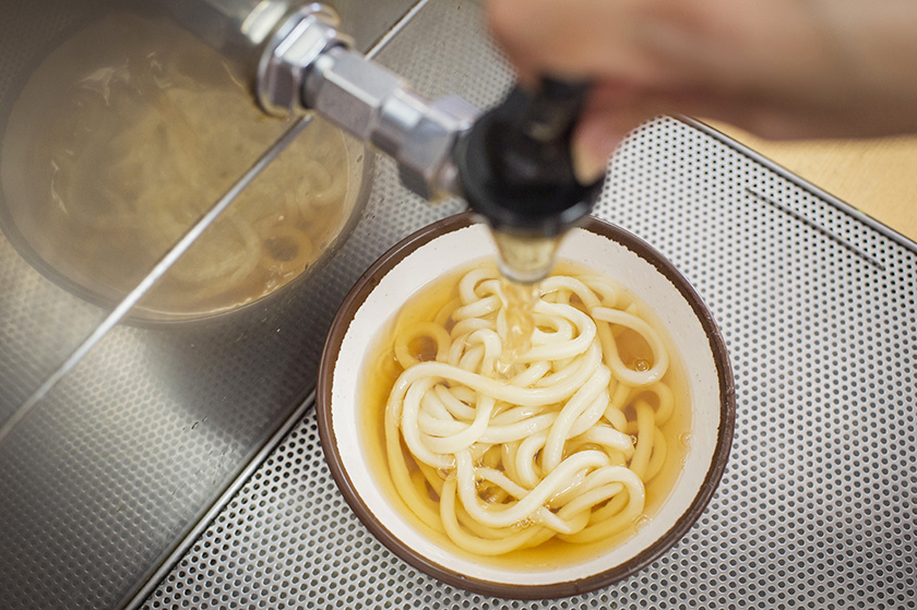 讃岐うどん「セルフうどん店」でだしを入れる様子