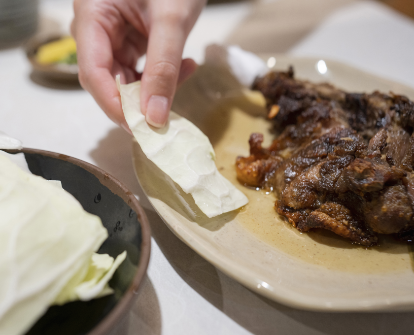 キャベツを骨付鳥の鶏油につける様子